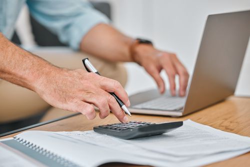 Foto: Männerhände auf PC und Taschenrechner